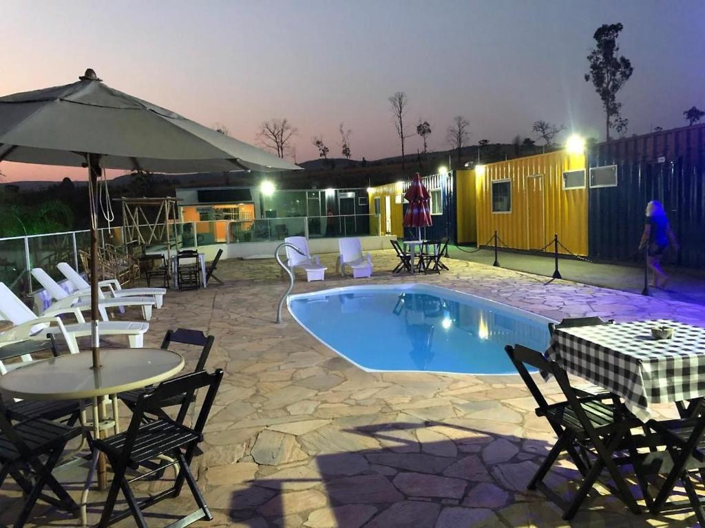 a patio with a pool and chairs and an umbrella at ROYAL CONTAINER HOTEL in Capitólio