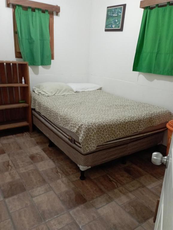 1 cama en una habitación con cortinas verdes en Finca Los 3 Laureles Nicaragua AgroEcolodge, en San Ramón