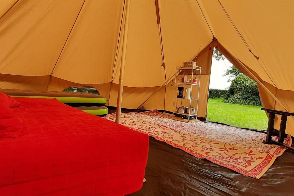 ein Schlafzimmer mit einem roten Bett in einem Zelt in der Unterkunft Sfeervolle Tipi tent dicht bij de kust. in Schagerbrug
