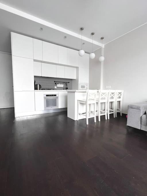 a kitchen with white cabinets and a table and chairs at Riga Modern Apartment in Rīga