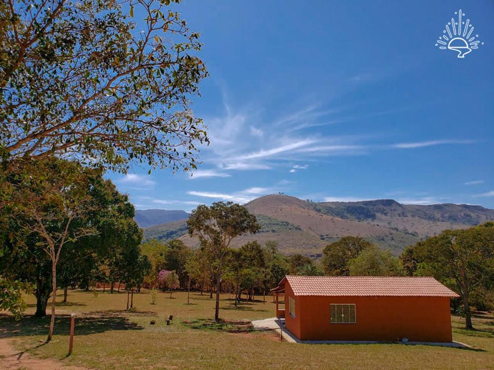 a small red house in a field with mountains in the background at Pousada Águas da Canastra in Vargem Bonita