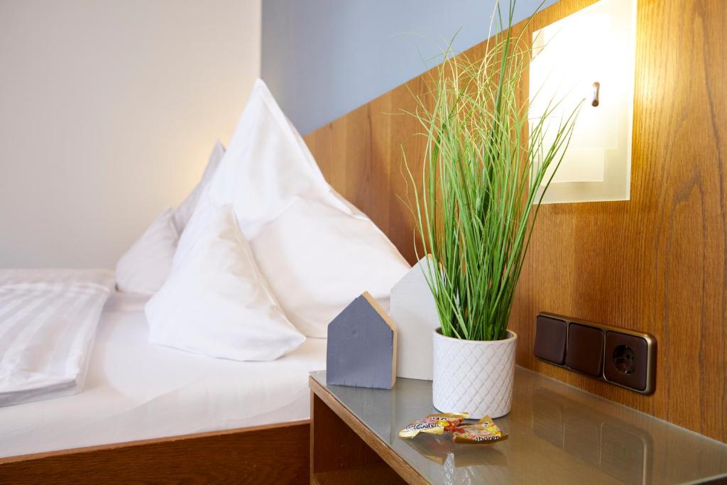 ein Schlafzimmer mit einem Bett mit einer Pflanze auf einem Tisch in der Unterkunft Gästehaus am Landhaus Friedrichsfehn in Edewecht