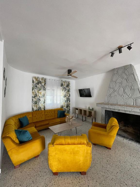 a living room with yellow furniture and a fireplace at Villa Paraiso in Cazalegas