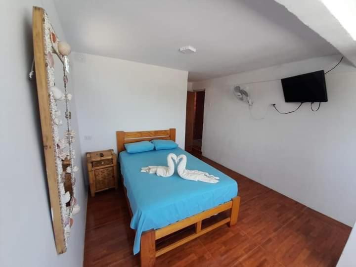 a bedroom with a bed with blue sheets and a tv at La palmera zorritos in Tumbes