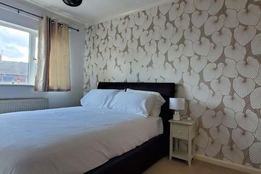 a bedroom with a bed and a wall covered in flowers at APNI HOMES! in Birstall