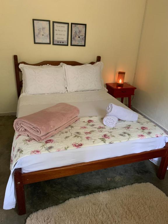 a bed with two pillows and a lamp on a table at Casinha de Campo com Lago Sítio Luar do Sertão in Bom Jardim