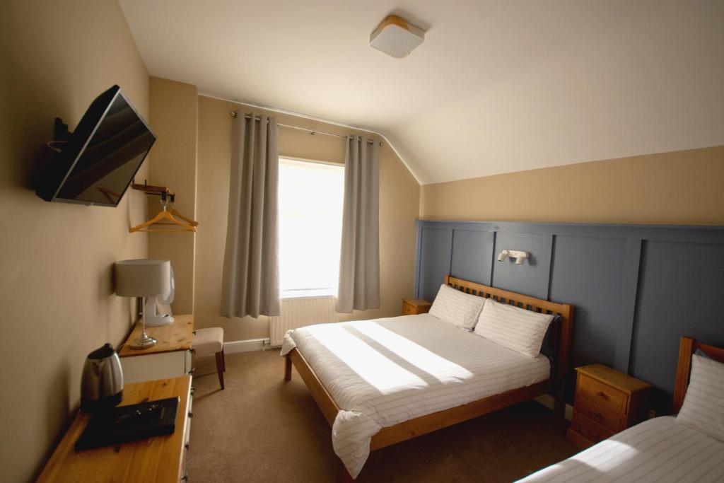 1 dormitorio con 2 camas y TV. en Salamander Guest House en Stratford-upon-Avon
