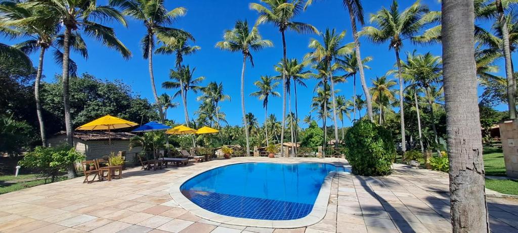 uma piscina no resort com palmeiras em Porto do Sol - Chalé 07 em Pipa