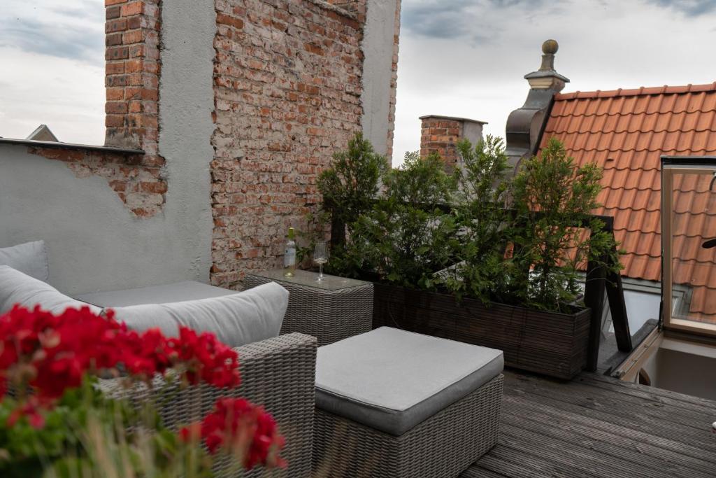 a patio with wicker furniture and flowers on a balcony at Gotyk na dotyk z tarasem na dachu in Toruń