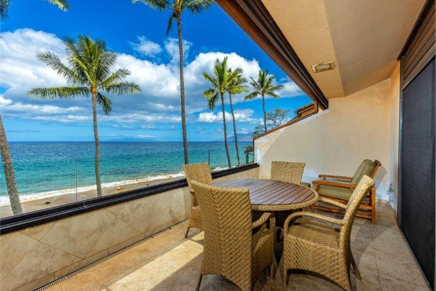 a table and chairs on a balcony with a view of the ocean at MAKENA SURF #B304 condo in Wailea