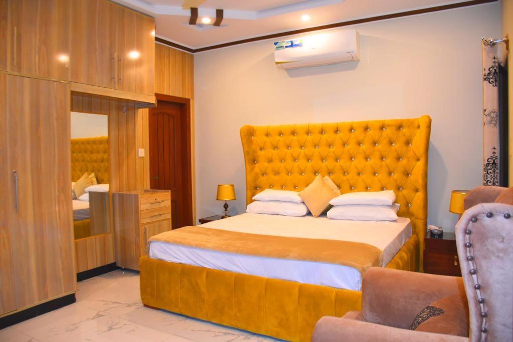 um quarto com uma cama grande e uma cadeira em Britannia House near Islamabad International Airport and Motorway em Islamabad