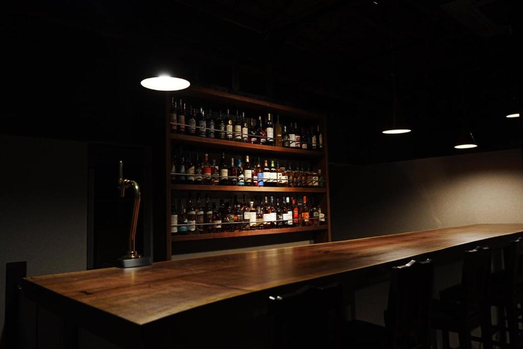 a bar with a wooden counter with bottles of alcohol at root hakone in Hakone