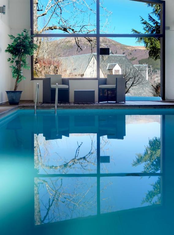 a swimming pool with a view of a house at Hotel Le Panorama in Le Mont-Dore