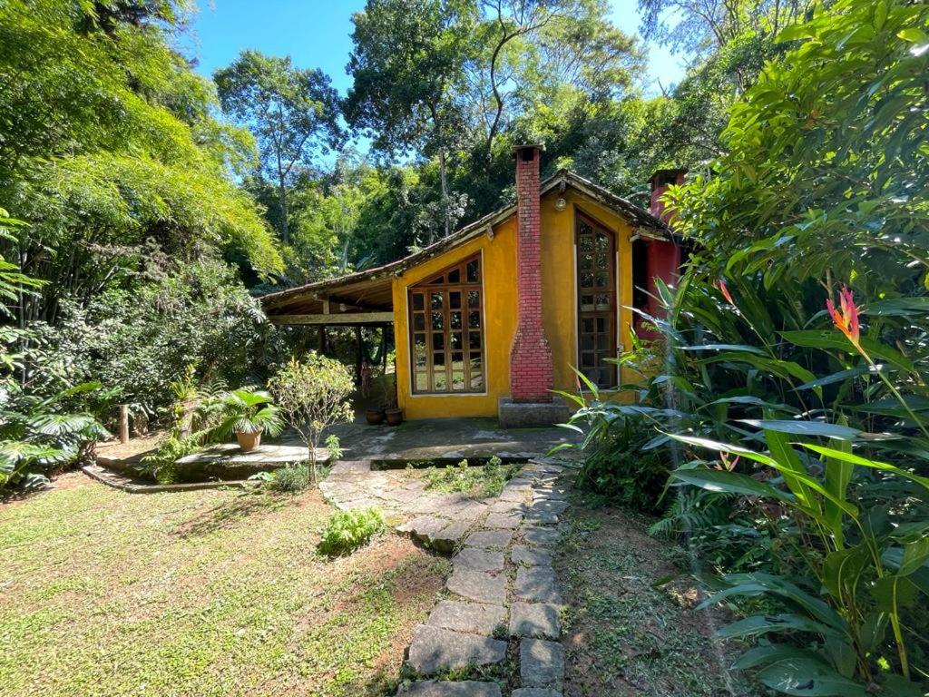 una casa amarilla en medio de un jardín en Casa linda no sítio, en Duque de Caxias