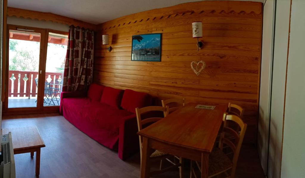 ein Wohnzimmer mit einem roten Sofa und einem Tisch in der Unterkunft Appartement coeur de station village Saint Francois Longchamp in Saint-François-Longchamp