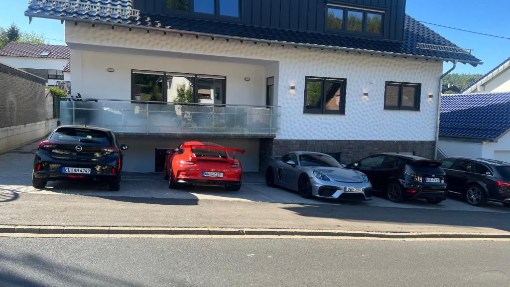 un grupo de autos estacionados frente a una casa en NRing Villa am Nürburgring, en Adenau
