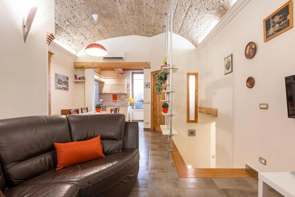 a living room with a leather couch and a kitchen at Sun Flowers House in Pitigliano