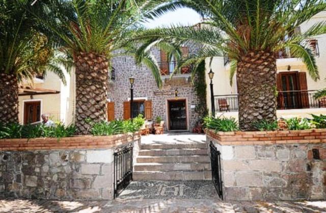 a house with two palm trees in a courtyard at Hotel Molyvos I in Mithymna