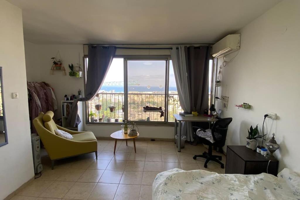 a bedroom with a large window and a desk and chairs at Sea view apartment in Haifa