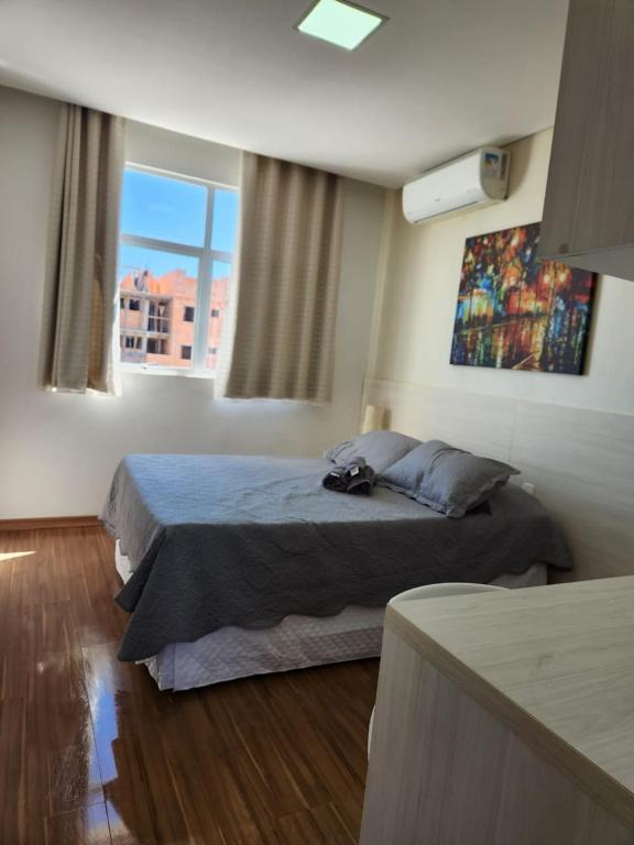a bedroom with a bed and a large window at Flats da Júnia - ótimo beneficio com wifi, ar, tv, frigobar in Lagoa Santa