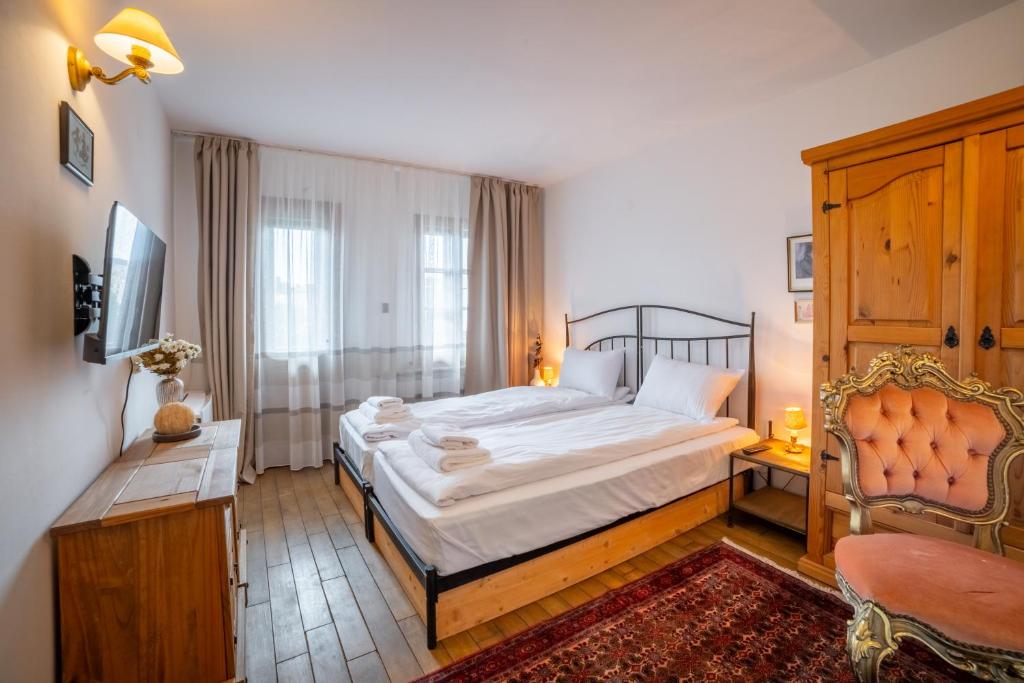 a bedroom with a large bed and a chair at Four Riders Guest House in Veliko Tŭrnovo