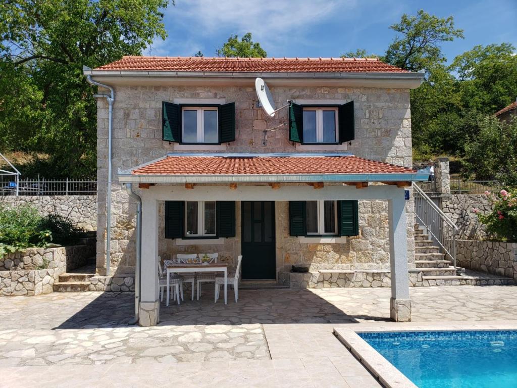 uma pequena casa com uma mesa e uma piscina em Villa Kula em Bajagić