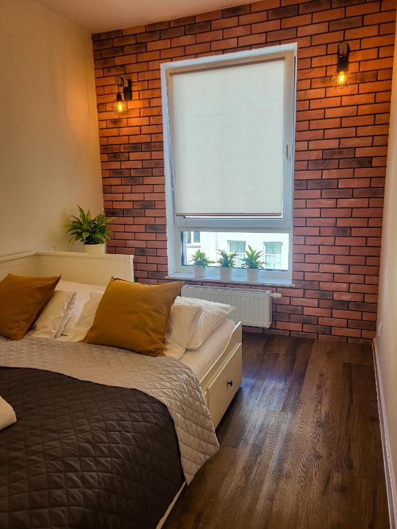 a bedroom with a bed and a brick wall at Apartament Ceglany in Legnica