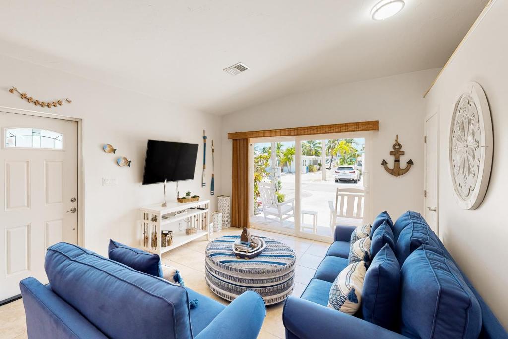 uma sala de estar com sofás azuis e uma televisão em Coastal Charm Hideaway em Key Colony Beach
