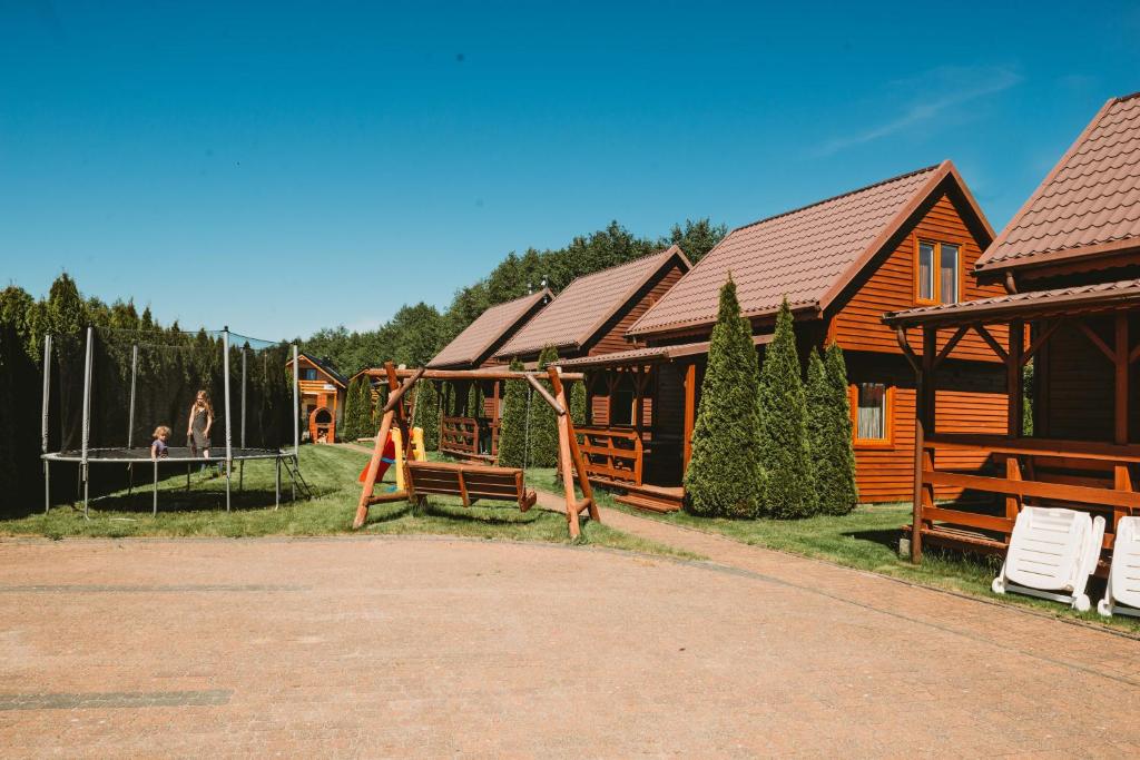 a log cabin with a playground and a house at Domki U Edzia in Kopalino