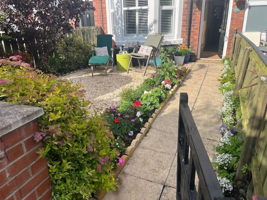 a garden with chairs and flowers next to a house at Stunning Whitley Bay apartment in Whitley Bay