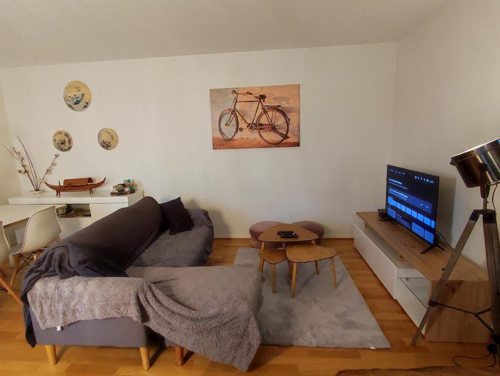 sala de estar con sofá y bicicleta en la pared en Perle rare, en Saint-Gratien