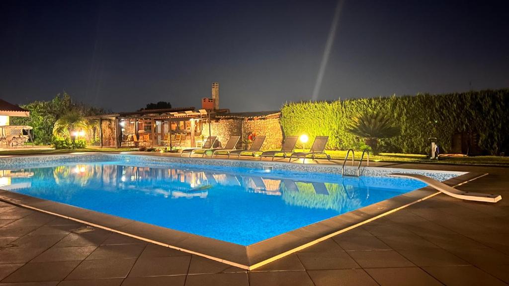 a large swimming pool with blue water at night at Villa Vedesa in Gallipoli
