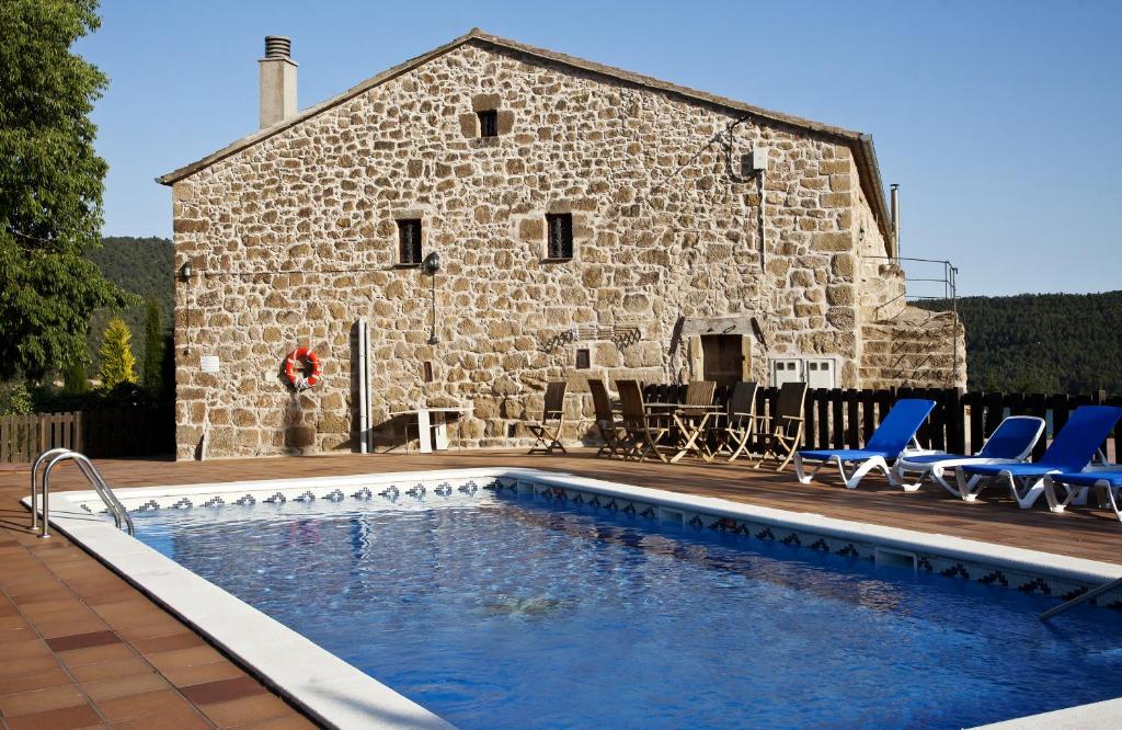 una piscina di fronte a un edificio in pietra di Masia Mas d'en Bosch a Lleida