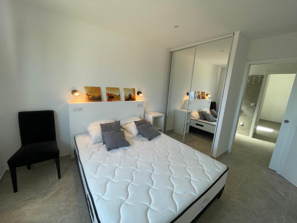 a bedroom with a white bed and a black chair at Villa de standing in Calvi