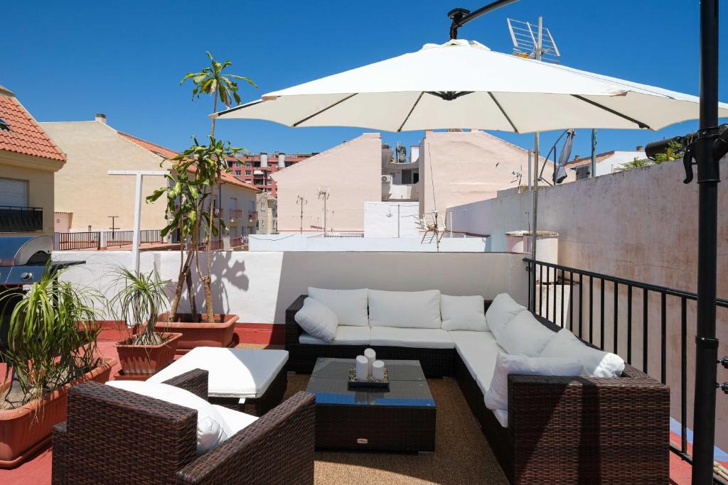 a patio with a couch and an umbrella on a balcony at Andalucian house, few minutes from the beach in Fuengirola