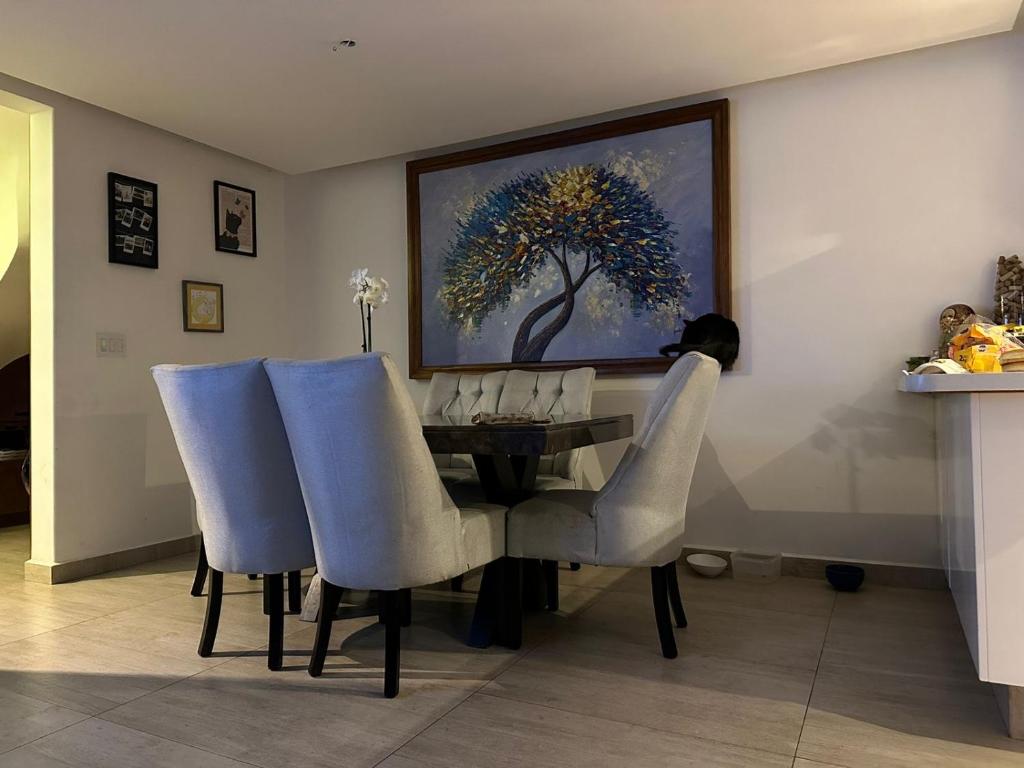 a dining room table with chairs and a painting on the wall at Casa helenico in Mexico City