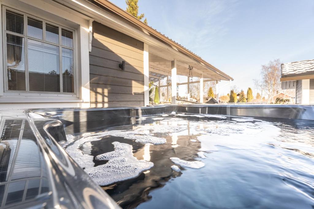 a pool of water in front of a house at Villa Einola- modern rivercottage with jacuzzi in Pori