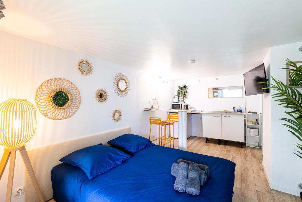 a bedroom with a blue bed and a kitchen at Studio charmant & champêtre in Auch