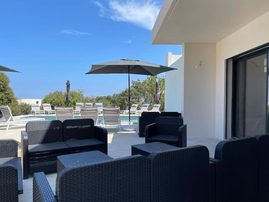 a patio with chairs and an umbrella and a pool at Villa de standing in Calvi