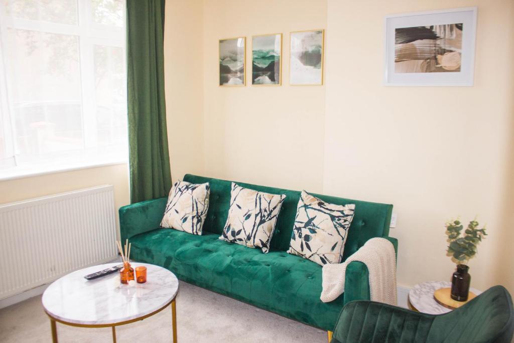 a living room with a green couch and a table at 3 beds - Spacious garden in Streatham Vale