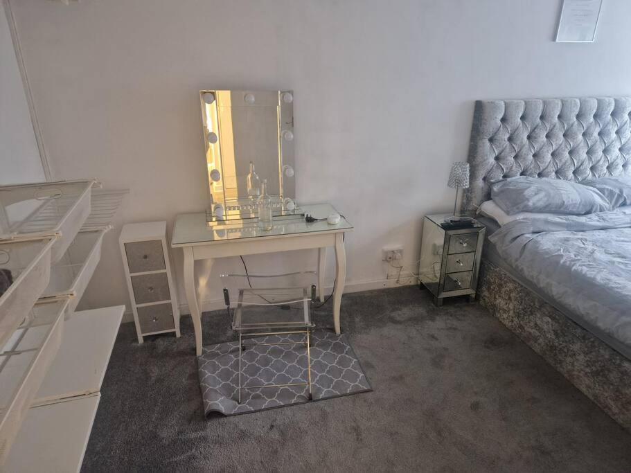 una camera da letto con scrivania, letto e specchio di Cosy one bed flat a Woodford