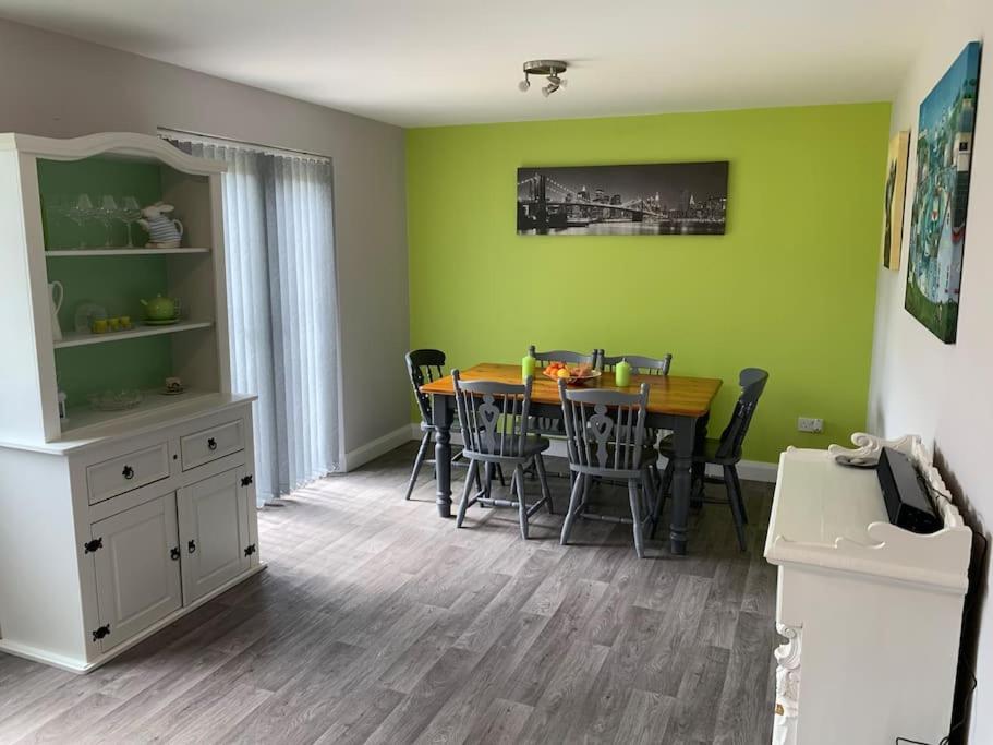een eetkamer met een tafel en stoelen en groene muren bij Gortamaddy House in Ballycastle