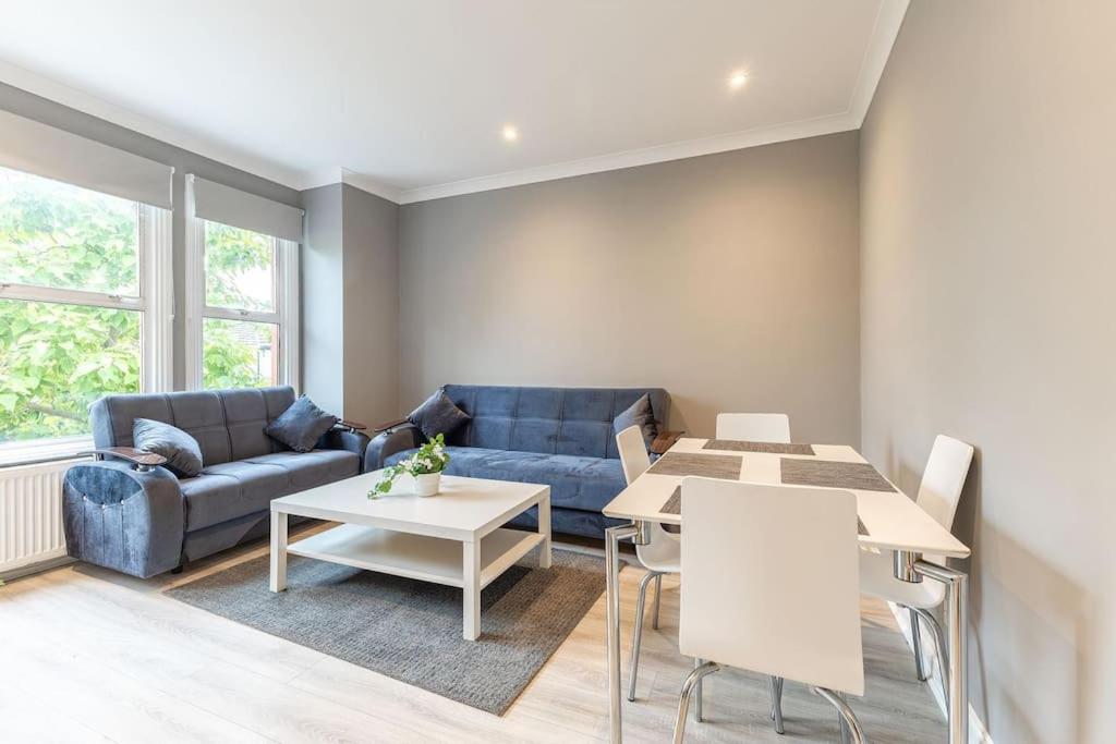 ein Wohnzimmer mit einem Sofa und einem Tisch in der Unterkunft Cozy 3-Bedroom Flat in Willesden Green London in London