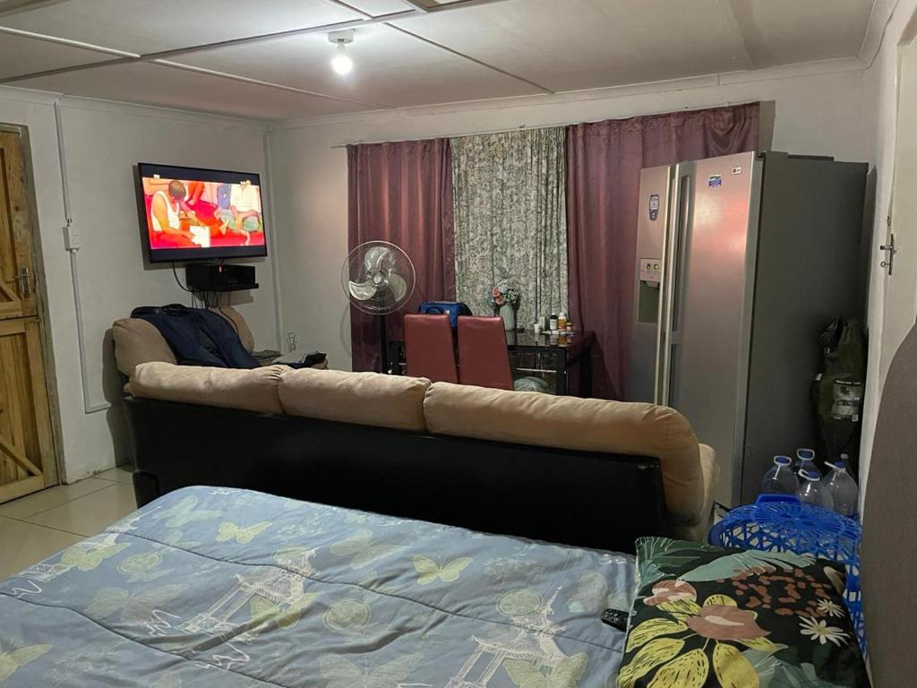 ein Wohnzimmer mit einem Bett und einem TV sowie ein Zimmer in der Unterkunft Mary's Crip in King Williamʼs Town
