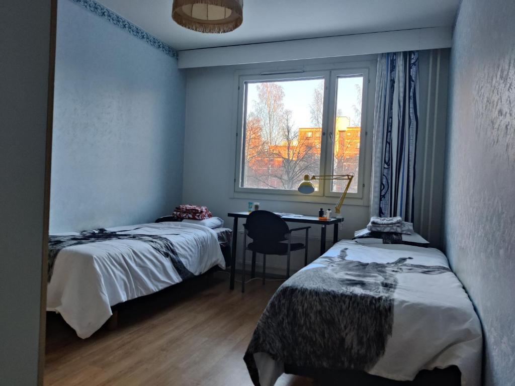 a bedroom with two beds and a desk and a window at Cozy budget room w/ balcony in shared apartment in Vantaa