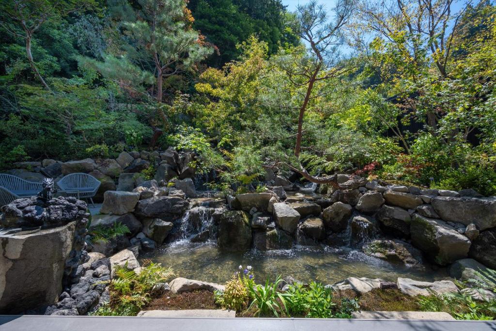 a waterfall in a garden with rocks and trees at Bessho Onsen Midoriya in Ueda