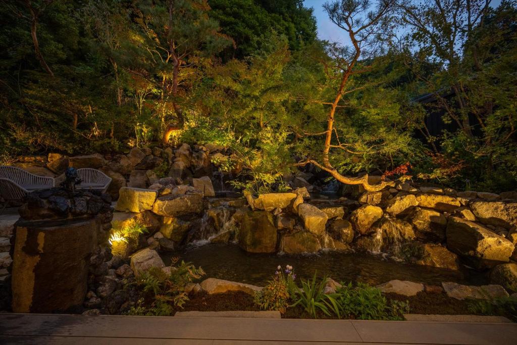 a waterfall in a garden with rocks and trees at Bessho Onsen Midoriya in Ueda