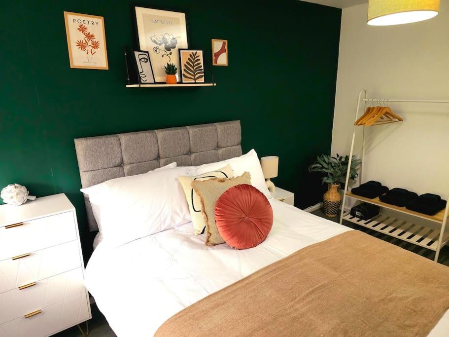 a bedroom with a large bed with a green wall at Homebird Property - Buckton House in Leeds