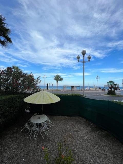 une table et des chaises avec un parasol à côté d'une clôture dans l'établissement Jardin sur la Promenade des Anglais, à Nice