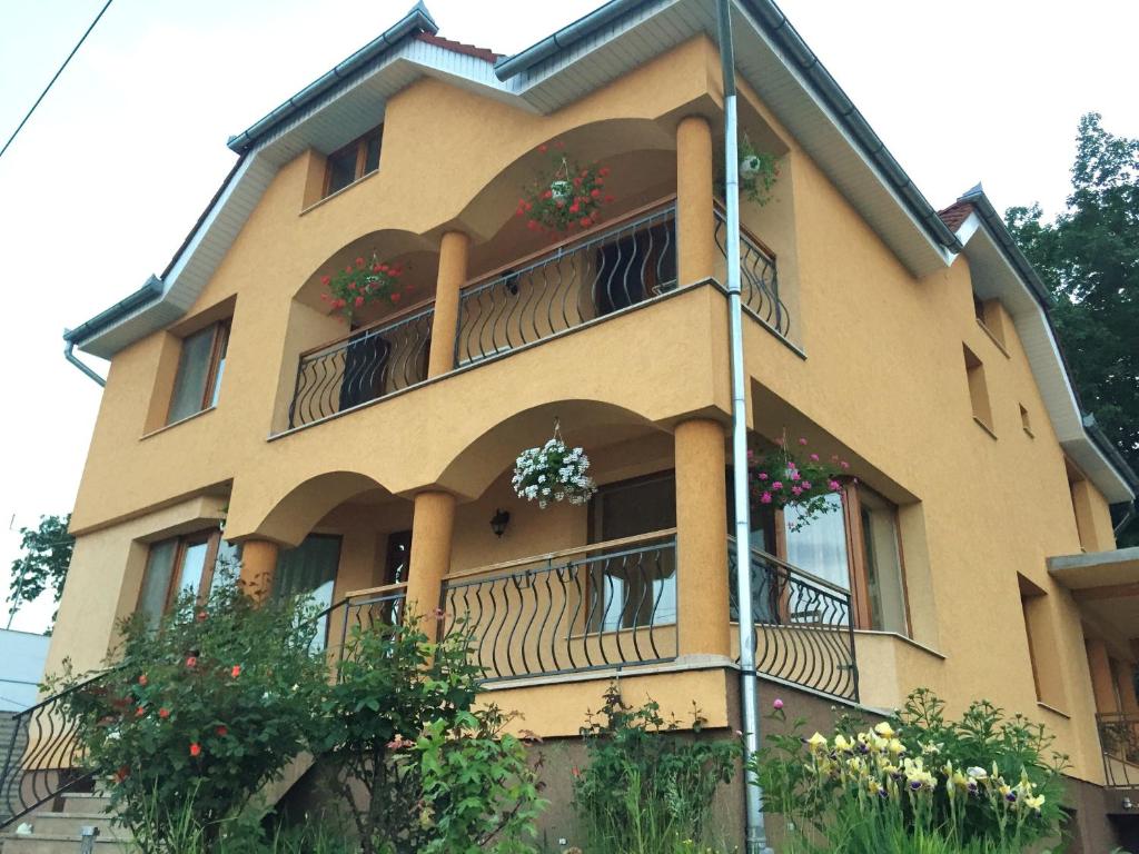 un bâtiment jaune avec des fleurs sur les balcons dans l'établissement Casa Teodora, à Băile Felix